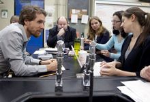 Six adults in the science lab classroom sitting around a table in discussion