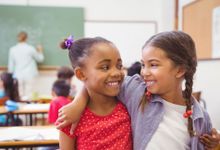 photo of two students smiling at each other in a classroom