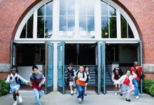 8名小学生正微笑着从三扇敞开的门中跑出教学楼。