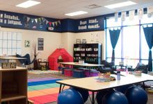 一个大的，没有学生的教室，有大的蓝色弹性球，沙发椅，折叠椅，帐篷，板条箱，垫子和其他独特的家具。