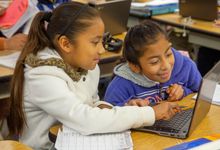 Two elementary students work on a Chromebook together