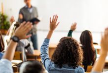 High school students raising hands in class