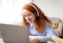 Elementary student at home on laptop with headphones