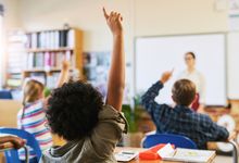 Elementary school classroom with student raising hand for teacher