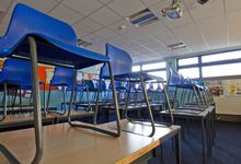 Empty blue chairs stacked on desks in a classroom