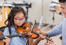 Photo of girl receiving instruction playing violin