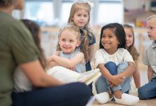 Preschool children listen while teacher reads a book