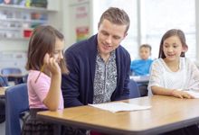 Elementary teacher helps student with writing assignment