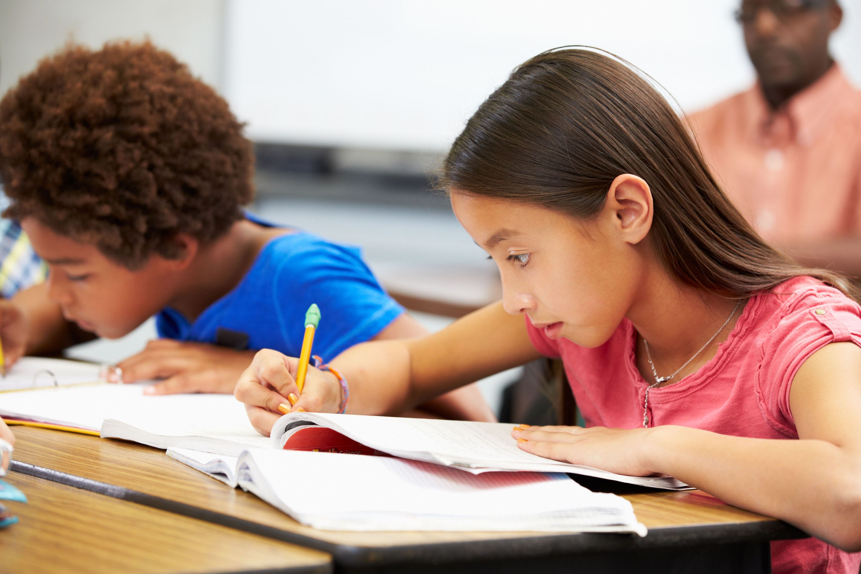  Two students working independently at their desks in a classroom.