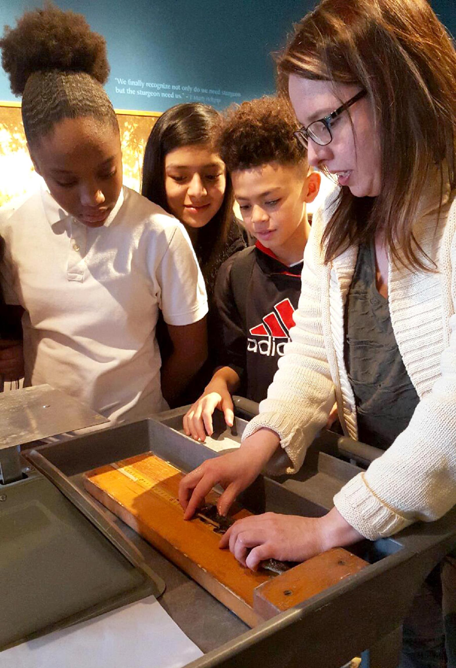 The museum’s resident scientist, Dr. Stephanie Ogren, shows students how to weigh native lake sturgeon. The endangered fish lives in the river right outside the museum’s doors.
