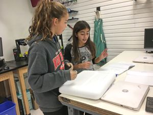 Two seventh grade students consider materials for their pretotype for a food transportation system.