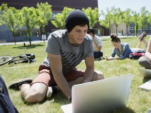 Student coding outdoors on a laptop 