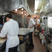 A photo of chefs working in close-quarters in a narrow kitchen.