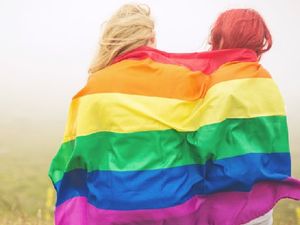 Two young adults wrapped in a rainbow flag