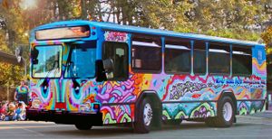 An exterior shot of a tie-dye painted bus parked on the street with eyes painted on the front and "Art" painted on the side.
