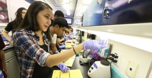 High school students are doing science laboratory work inside of a bus.