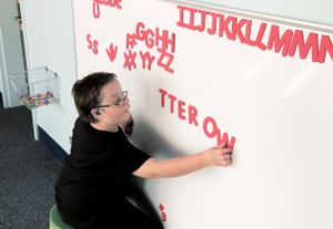 A student arranges magnetic letters on a whiteboard.