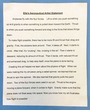 A second-grade student's typed artist statement glued against blue construction paper explaining the four forces of flight -- lift, gravity, drag, and thrust -- and how making art with a salad spinner used two of the forces.