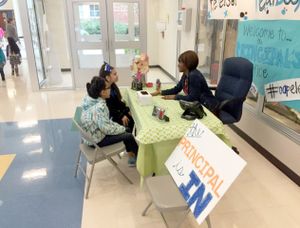 A principal chats with two elementary students in the school hallway.